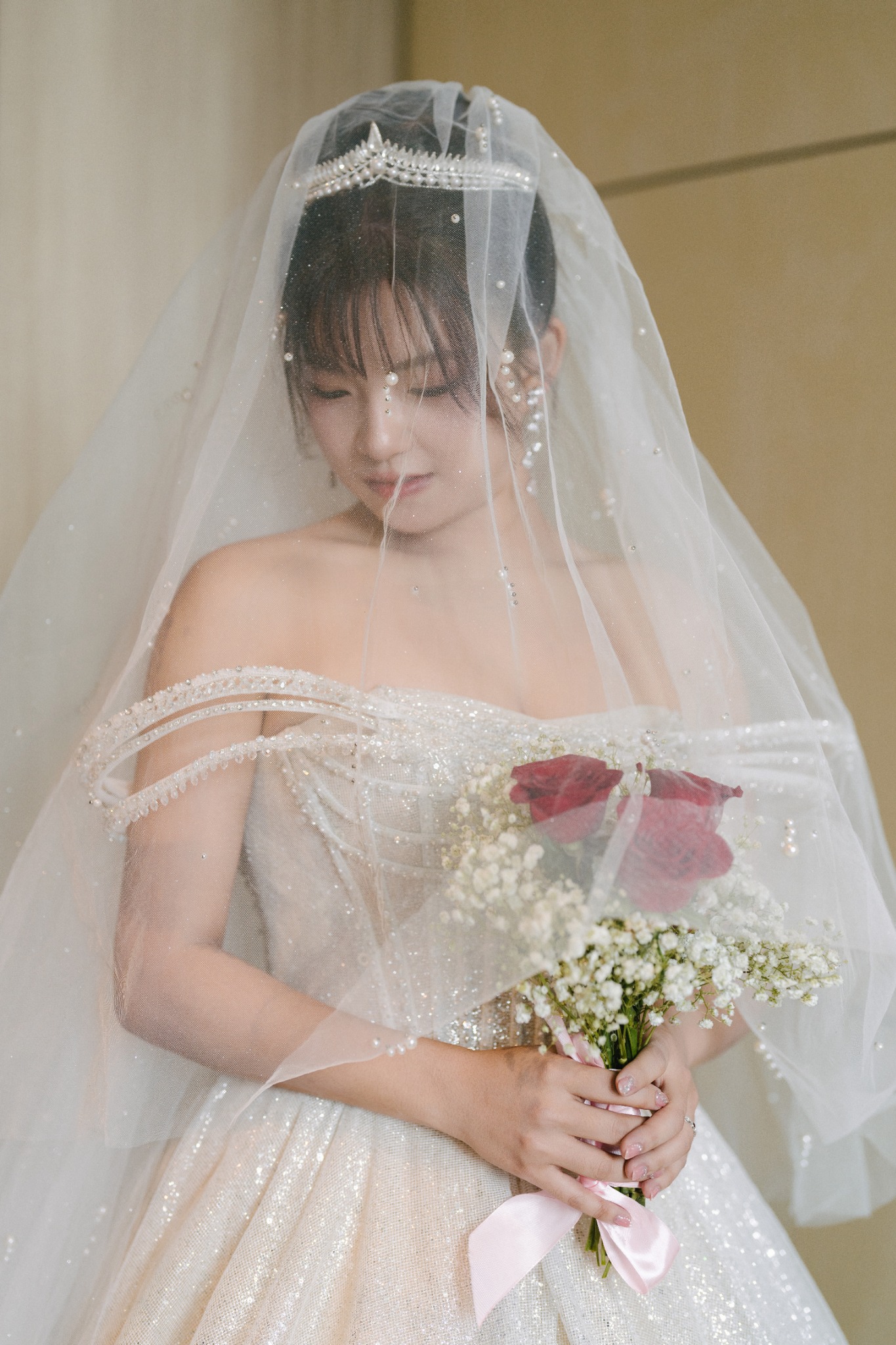 Bride holding red roses beneath her veil