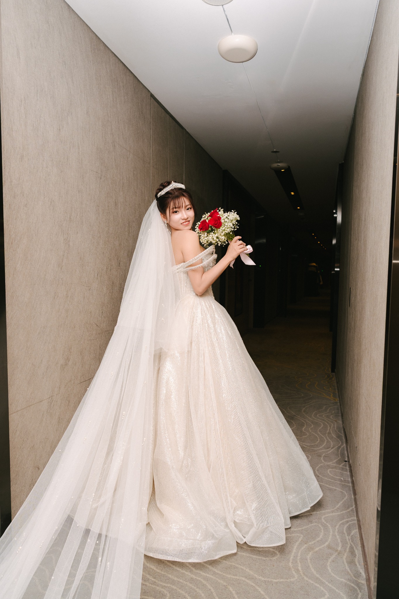 Bride in a long veil walking through a hotel corridor