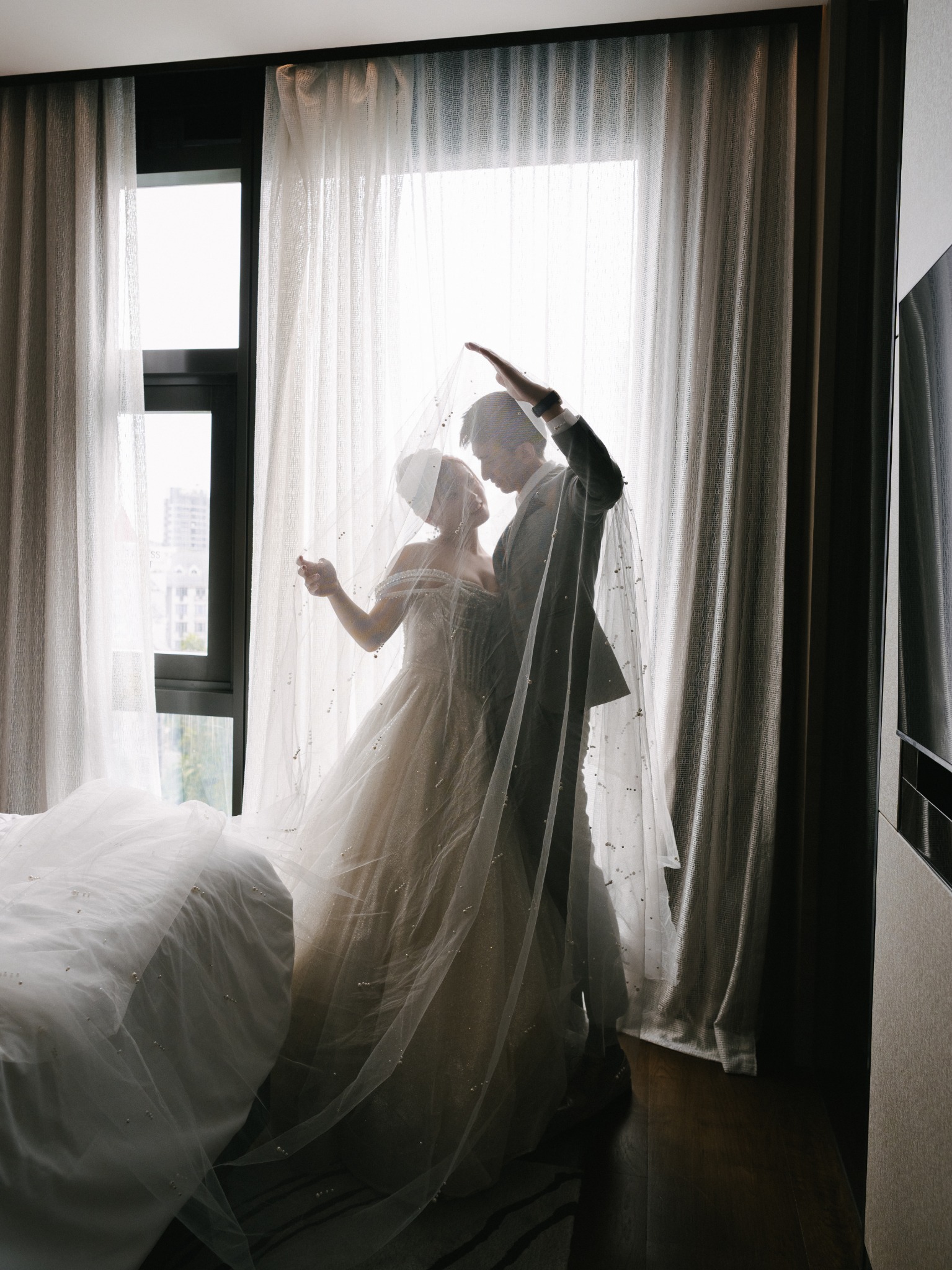 Newlyweds dancing by a bright hotel window
